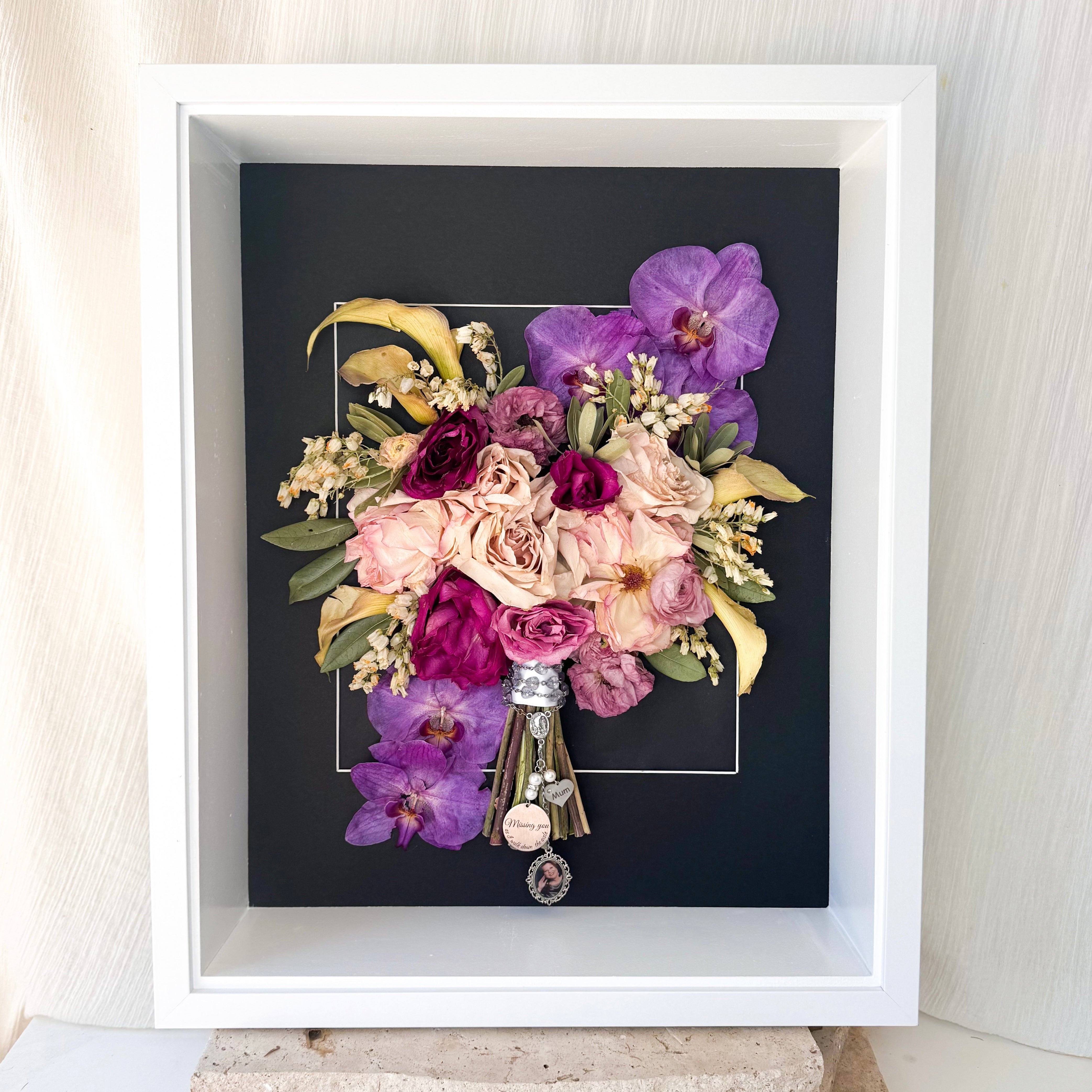custom-flower-framing-3d-shadow-box
Preserved orchid, lily, bright wedding bouquet set in 40x50cm 3d white frame black matboard with memorial charms