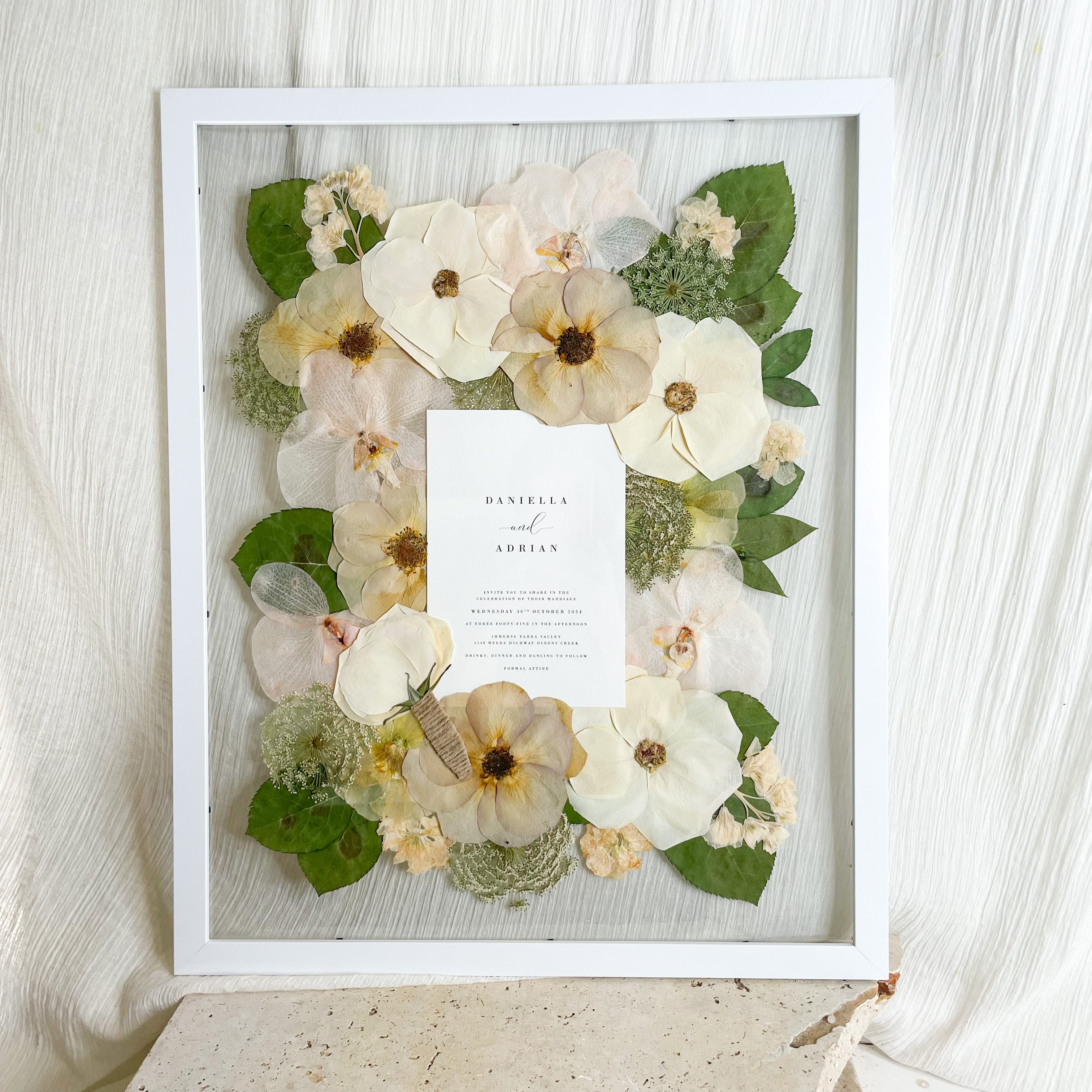 Preserved pressed wedding bouquet - white and green flowers roses set in a floating frame mount with wedding invitation
